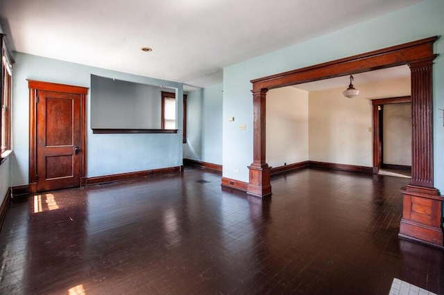 spare room with baseboards, wood finished floors, and ornate columns