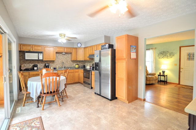 kitchen featuring sink, tasteful backsplash, a textured ceiling, appliances with stainless steel finishes, and ceiling fan