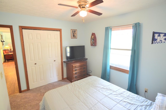 carpeted bedroom featuring ceiling fan, a closet, and a textured ceiling