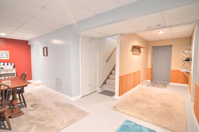 interior space with wooden walls and a drop ceiling