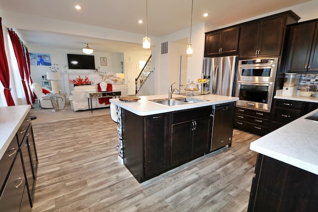 909 Riesling Ct, Walton, KY 41094 - kitchen featuring stainless steel appliances, an island with sink, light wood-style floors, light countertops, and open floor plan