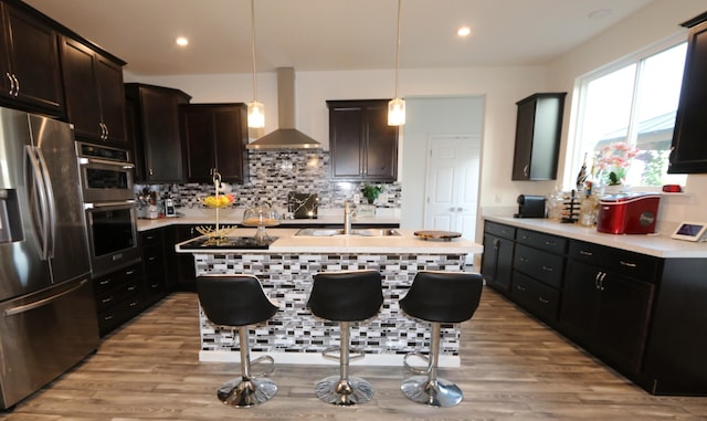 909 Riesling Ct, Walton, KY 41094 - kitchen featuring appliances with stainless steel finishes, wall chimney range hood, light countertops, light wood-style flooring, and recessed lighting