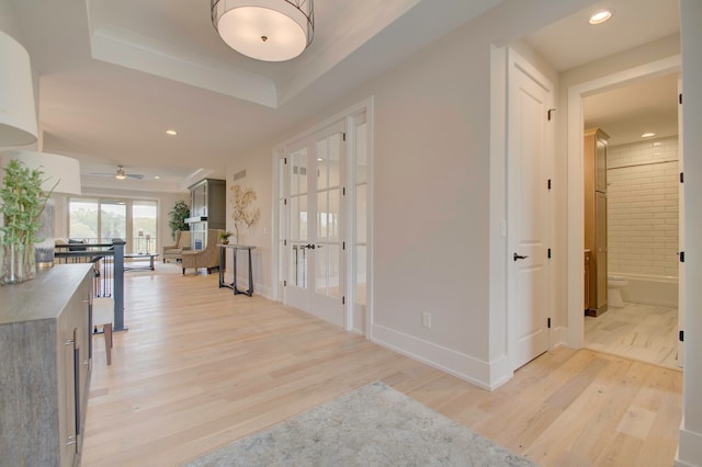 entryway featuring light wood-type flooring, a raised ceiling, and ceiling fan