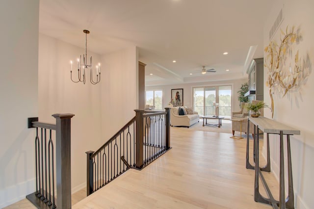 hall with light wood-type flooring and a notable chandelier