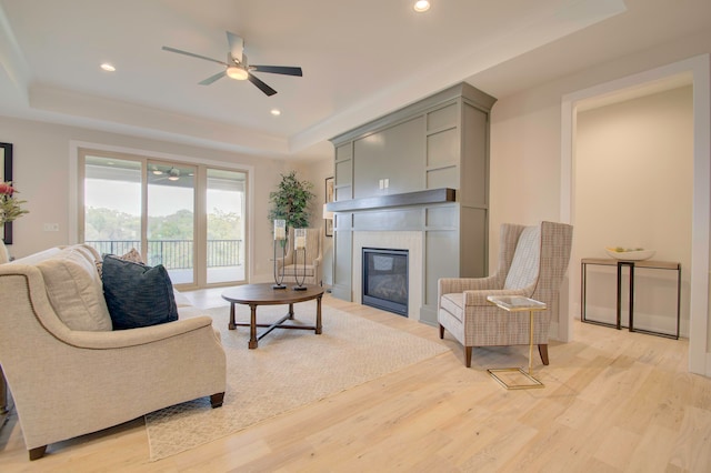 living room featuring ceiling fan, a tray ceiling, and light hardwood / wood-style floors