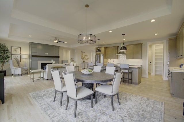 828 Fairbanks Ln, Southgate, KY 41071 - dining area with ceiling fan with notable chandelier, light wood-style flooring, and a raised ceiling