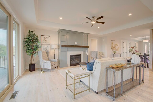 living room with ceiling fan, a fireplace, and light hardwood / wood-style floors