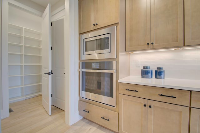 kitchen featuring light brown cabinetry, backsplash, light hardwood / wood-style floors, and appliances with stainless steel finishes