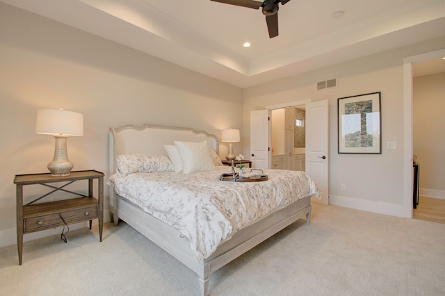 bedroom with ceiling fan, light colored carpet, and connected bathroom