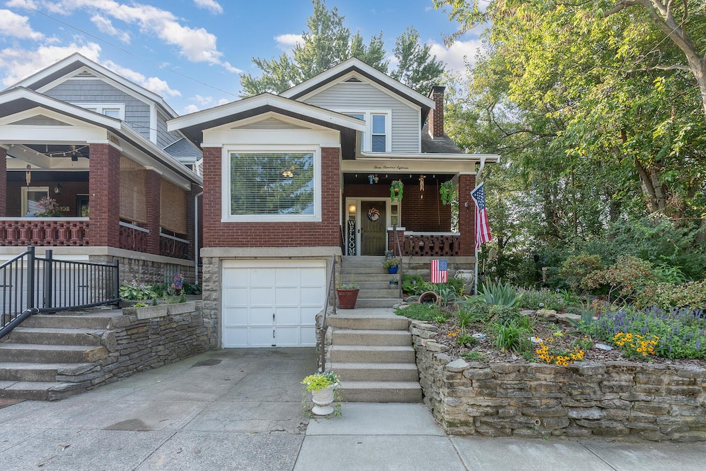 view of front of house with a porch, an attached garage, brick siding, driveway, and a chimney