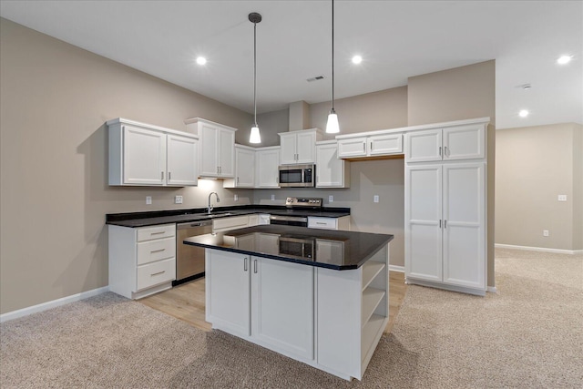 kitchen featuring appliances with stainless steel finishes, white cabinetry, a kitchen island, light carpet, and decorative light fixtures