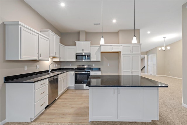 kitchen with pendant lighting, sink, appliances with stainless steel finishes, white cabinetry, and a center island