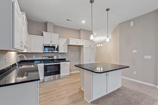 kitchen with a kitchen island, appliances with stainless steel finishes, decorative light fixtures, white cabinetry, and sink