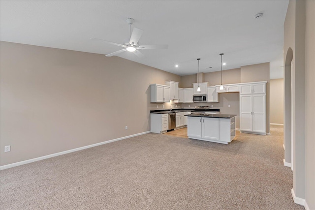 kitchen with pendant lighting, ceiling fan, white cabinetry, stainless steel appliances, and a center island