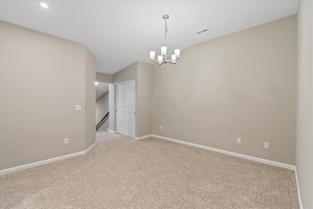 carpeted empty room featuring a notable chandelier