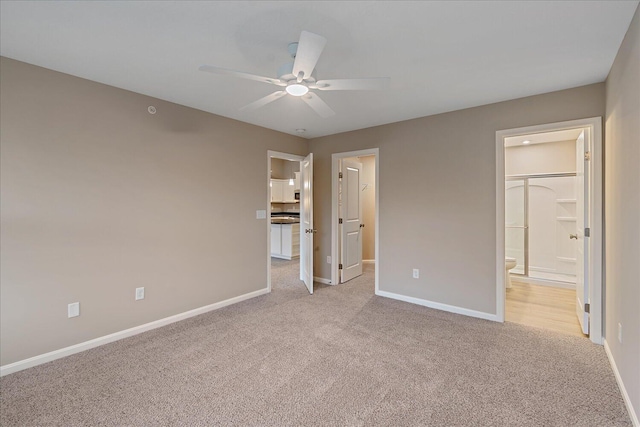 unfurnished bedroom with ceiling fan, ensuite bath, and light carpet