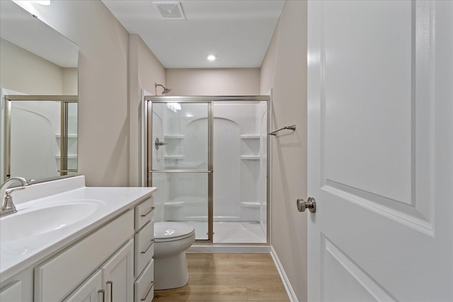 bathroom featuring hardwood / wood-style flooring, vanity, toilet, and walk in shower