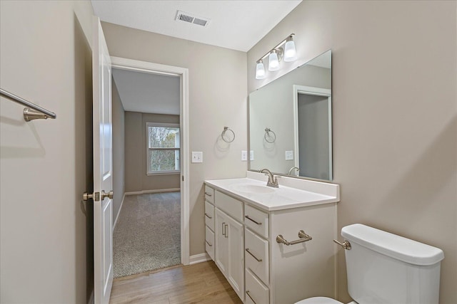 bathroom with hardwood / wood-style flooring, vanity, and toilet