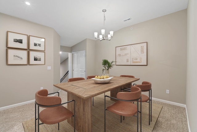 carpeted dining room with a chandelier and vaulted ceiling