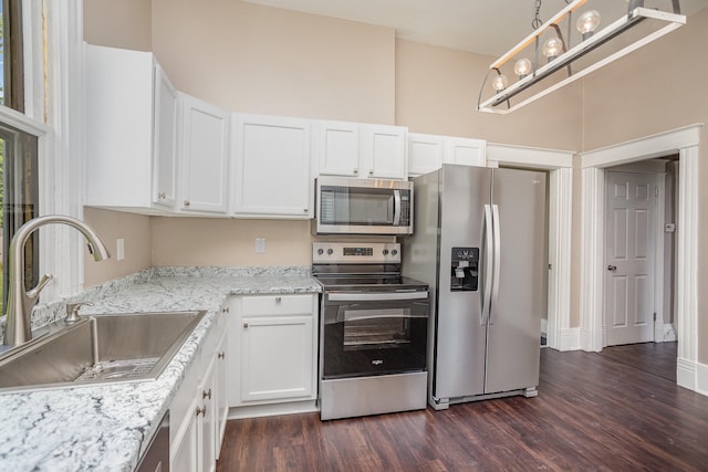 kitchen with sink, dark hardwood / wood-style floors, stainless steel appliances, and light stone countertops