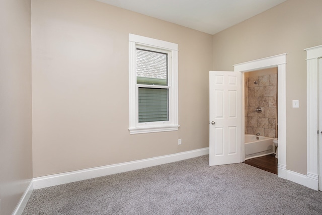 unfurnished bedroom featuring ensuite bath and carpet flooring