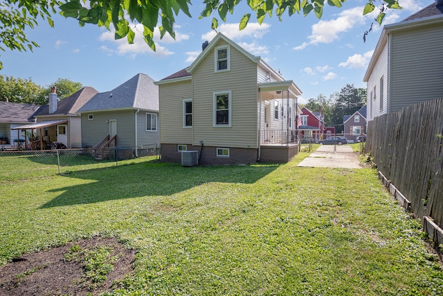 rear view of property with central air condition unit and a lawn