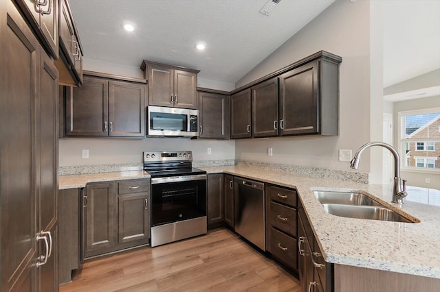 kitchen with light stone counters, sink, light hardwood / wood-style flooring, and appliances with stainless steel finishes