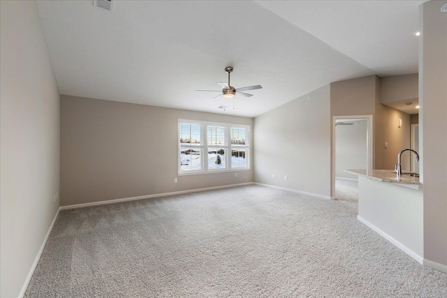 empty room featuring lofted ceiling, sink, light carpet, and ceiling fan