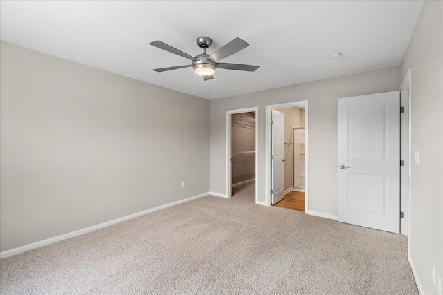 unfurnished bedroom featuring ensuite bathroom, a spacious closet, ceiling fan, light carpet, and a closet