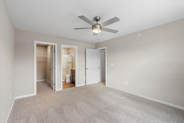 unfurnished bedroom featuring connected bathroom, carpet flooring, a spacious closet, ceiling fan, and a closet