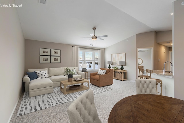 carpeted living room with vaulted ceiling, sink, and ceiling fan