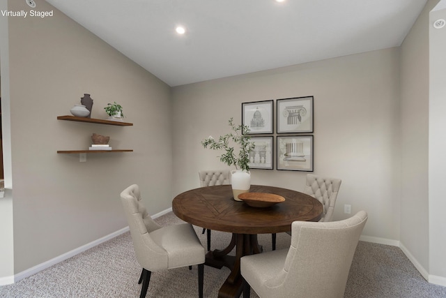 carpeted dining area featuring vaulted ceiling