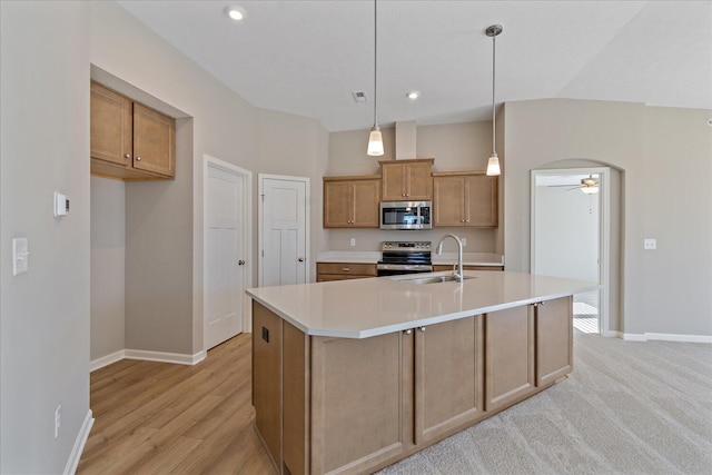 kitchen featuring appliances with stainless steel finishes, decorative light fixtures, an island with sink, sink, and ceiling fan