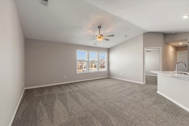 unfurnished living room featuring vaulted ceiling, sink, ceiling fan, and dark carpet