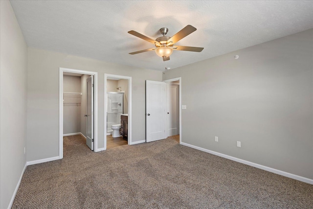 unfurnished bedroom with a closet, a walk in closet, carpet, and a textured ceiling