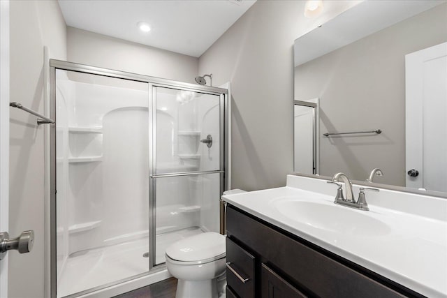 bathroom with a stall shower, vanity, and toilet