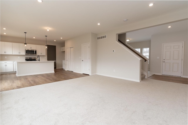 unfurnished living room with wood-type flooring and sink