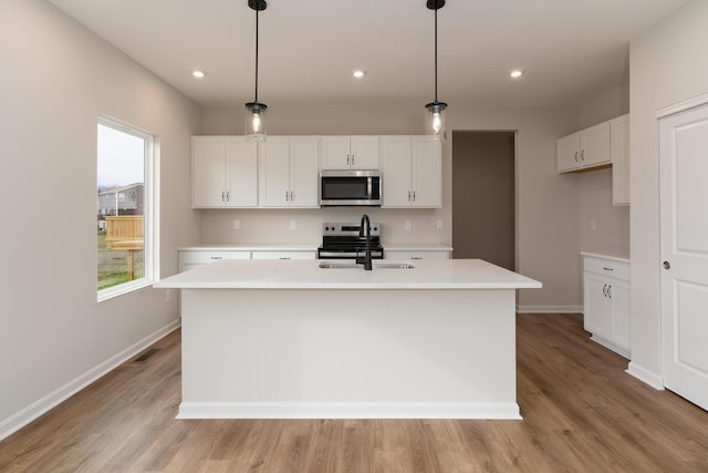 kitchen with sink, decorative light fixtures, a kitchen island with sink, white cabinets, and appliances with stainless steel finishes