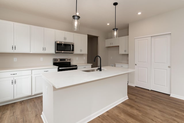 kitchen with a center island with sink, pendant lighting, sink, and stainless steel appliances