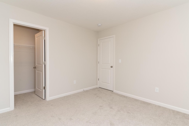 unfurnished bedroom with light carpet, a spacious closet, and a closet