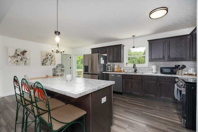 kitchen with stainless steel appliances, plenty of natural light, hardwood / wood-style floors, and decorative light fixtures