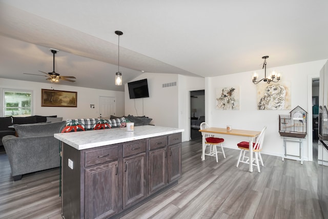 kitchen with ceiling fan with notable chandelier, pendant lighting, a center island, light hardwood / wood-style flooring, and dark brown cabinetry