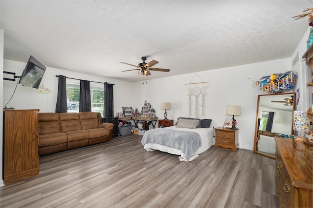 bedroom with ceiling fan, a textured ceiling, and wood-type flooring