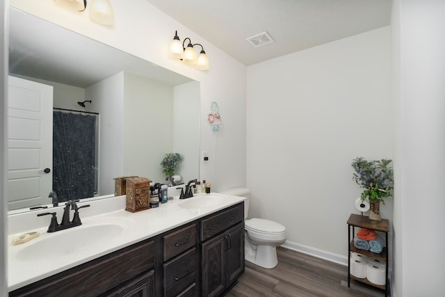 bathroom with double vanity, toilet, and wood-type flooring