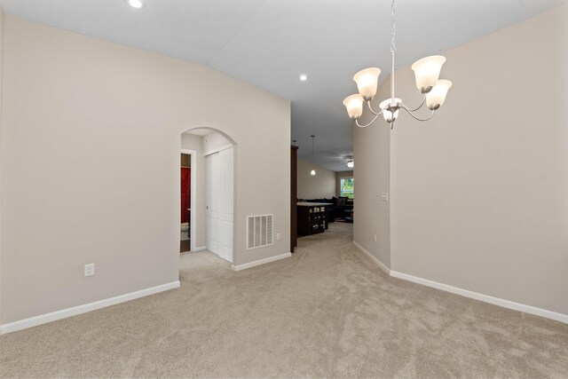 unfurnished dining area with ceiling fan with notable chandelier, lofted ceiling, and light colored carpet