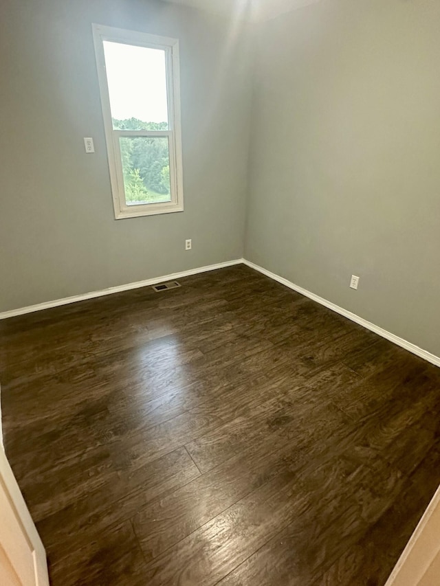 spare room with baseboards, visible vents, and dark wood-type flooring