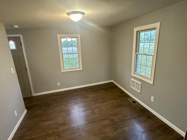 unfurnished room with dark wood-style floors, visible vents, and baseboards