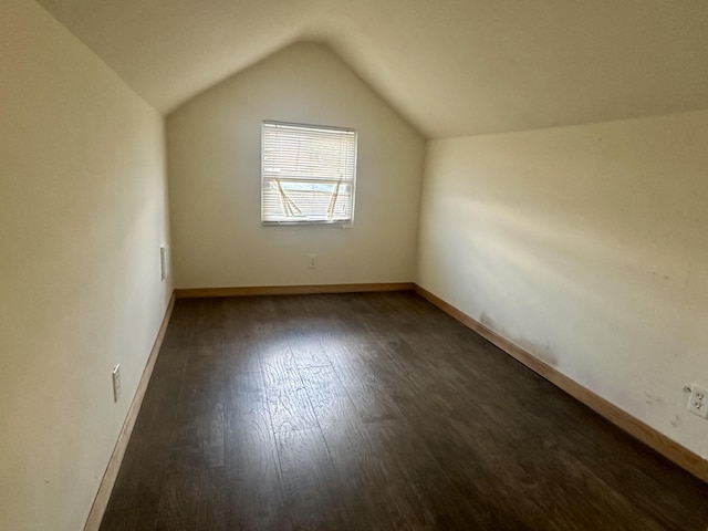 additional living space with vaulted ceiling, dark wood finished floors, and baseboards