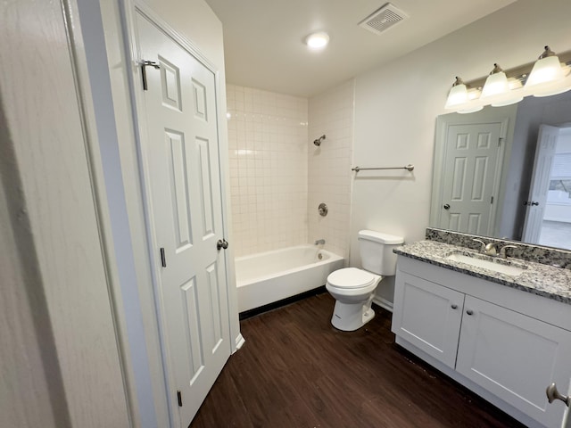 full bathroom featuring vanity, toilet, hardwood / wood-style flooring, and tiled shower / bath