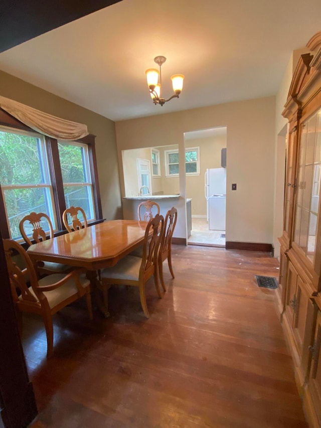 dining area with wood-type flooring and an inviting chandelier